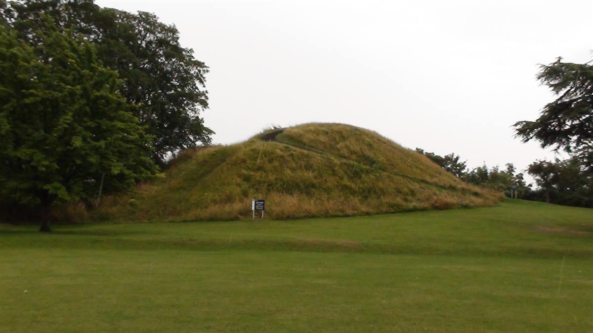 The grassy Castle Mound in Cambridge seen across open lawn