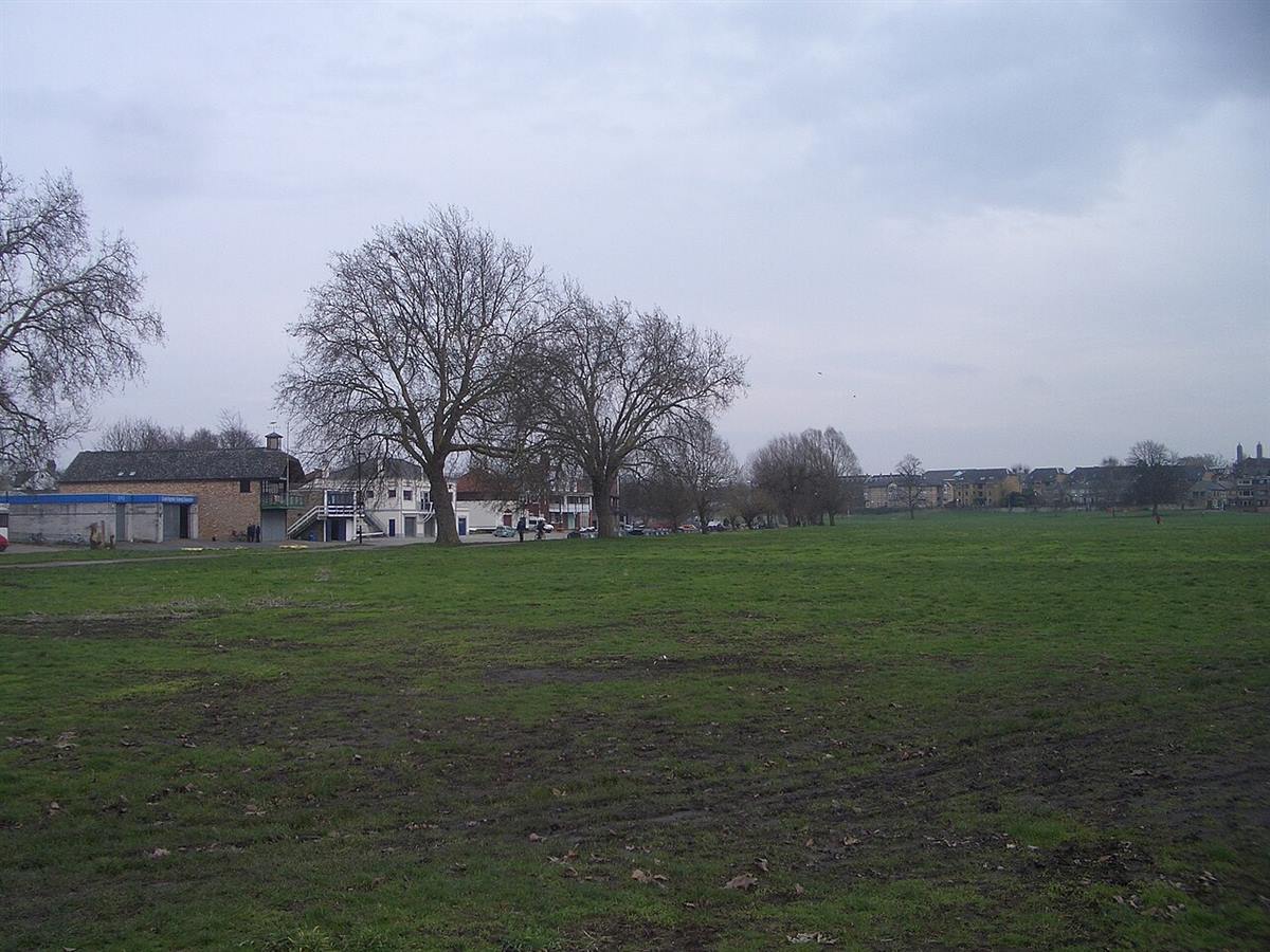 Open grassland on Midsummer Common, Cambridge, with boathouses and trees beyond